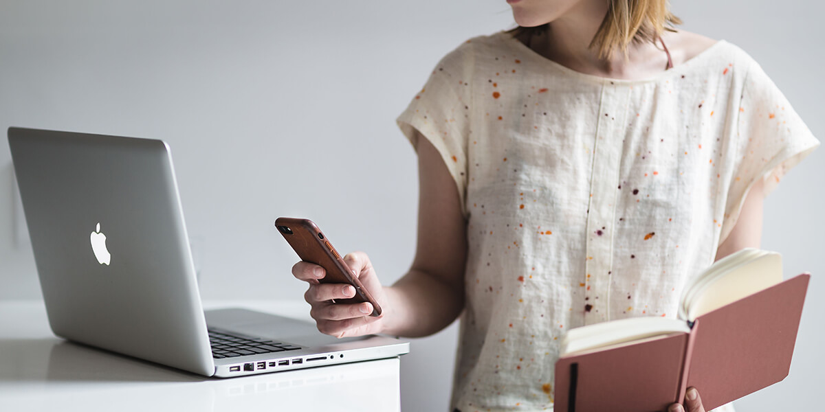 Woman watching a video on her phone in one hand while holding a book in the other. 3D rendering, design studio, 3D product, animation, character design, 2D animation, video production services, book trailer services, digital marketing services, motion design, motion graphics. RDV Media – Multimedia production company. Serving brands globally. New York, Los Angeles, California, Atlanta, USA, Dublin, Ireland, EU, London, England, UK, Doha, Qatar, UAE, Abu Dhabi, Ajman, Dubai, Fujairah, Ras Al Khaimah, Sharjah, and Umm Al Quwain.